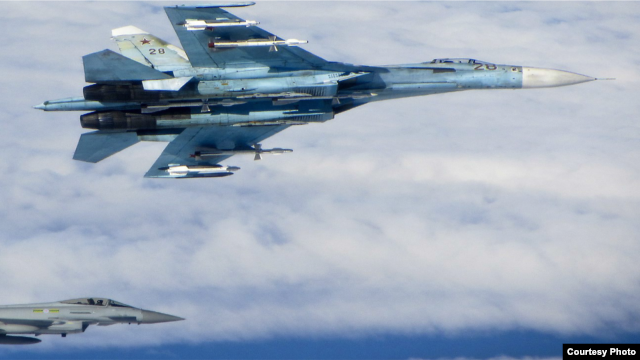 A Russian SU-27 Flanker aircraft banks away with a RAF Typhoon in the background. RAF Typhoons were scrambled on June 17 to intercept multiple Russian aircraft in international airspace as part of NATO’s ongoing Baltic Air Policing Mission. (UK Ministry o