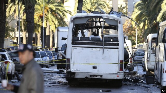 A man walks past the bus that exploded Tuesday in Tunis, Nov. 25, 2015. Tunisia's president declared a 30-day state of emergency across the country and imposed an overnight curfew for the capital after an explosion struck a bus.