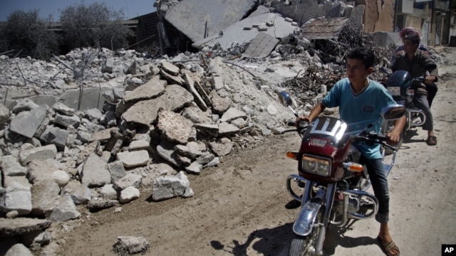 Syrians look at a destroyed house after it was hit by an air strike killing six Syrians in town of Tal Rifat on the outskirts of  Aleppo, Syria, Aug. 8, 2012. 