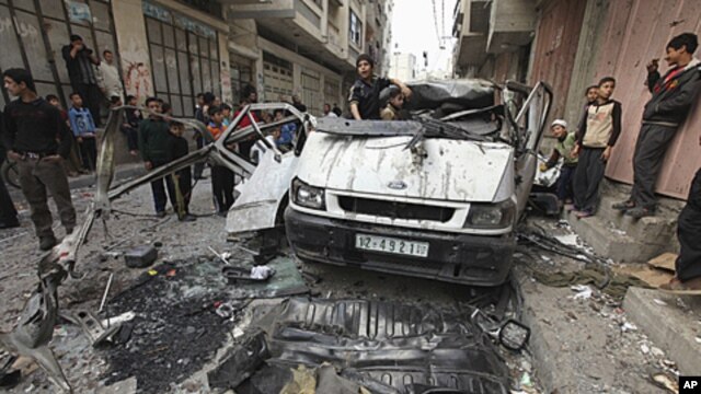 Palestinians inspect the damage to a vehicle after an Israeli air strike in Gaza City April 9, 2011