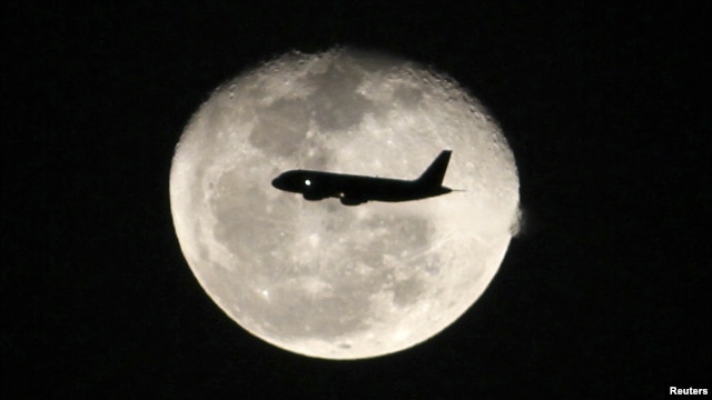 A passenger jet flies in front of the moon in Bogota, Colombia on Nov. 1, 2012. 