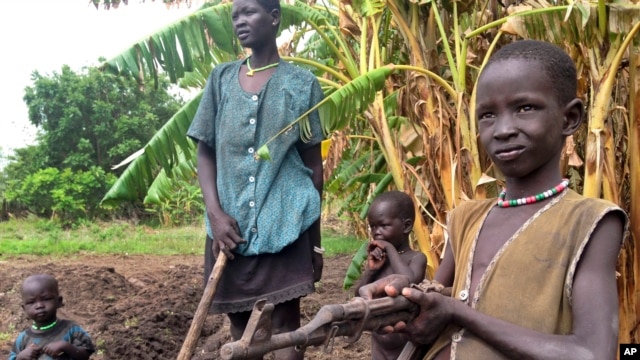 John Kawai Lam, 8, right, plays with a non-functioning automatic rifle that he found buried in the soil where he and his mother, Tabitha Nyanyun Ruach, were farming in May of 2014 in Unity state. New fighting erupted in Unity and Upper Nile states in January 2015, as South Sudan's conflict entered a second year. (AP Photo/Josphat Kasire)
