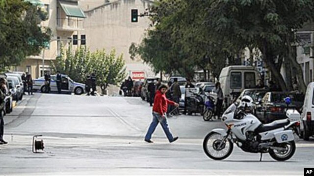 A police explosive expert, left, prepares a controlled blast of a suspicious package at a private delivery company in Athens, 02 Nov 2010