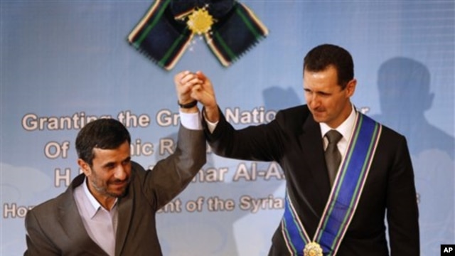 Iranian President Mahmoud Ahmadinejad, left, holds up the hand of his Syrian counterpart Bashar al-Assad after he was awarded Iran's highest national medal in a ceremony in Tehran, Iran, 2 Oct 2010