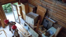 Workers from Second Chance remove all usable material from a log cabin which is scheduled to be torn down. (J. Taboh/VOA)