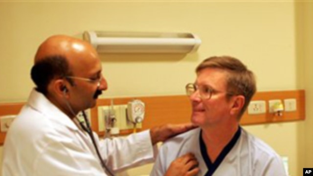 Indian doctor Praveen Chandra checks on an American patient Greg Goodell from Iowa after a his successful heart operation at a hospital in New Delhi, India, Saturday, Oct. 21, 2006,