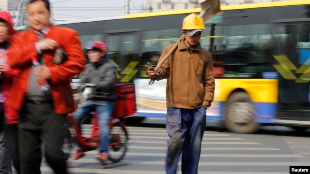 A worker crossing a street in Beijing, March 22, 2013.
