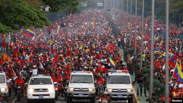 Thousands of people follow the funeral parade of Venezuela's late President Hugo Chavez in Caracas, March 15, 2013. 