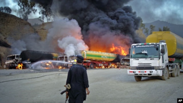 A security official stands near oil tankers - carrying fuel to US-led NATO forces in the northwestern tribal region of Khyber - that were set ablaze by a bomb blast near the main border crossing of Torkham, on the outskirts of Landikotal in Afghanistan, J