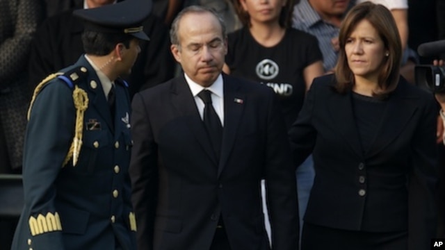 Mexico's President Felipe Calderon, center, reacts next to his wife Margarita Zavala after paying their respects to the relatives of the eight victims of a helicopter crash at the Campo de Marte military field in Mexico City, Thursday, Nov. 12, 2011.