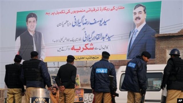 Hình treo trên tường là cựu Thủ tướng Pakistan Yousuf Raza Gilani (phải) và con trai Abdul Qadir Gilani 
