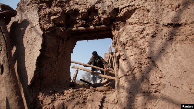 A resident collects items from the rubble of a house after it was damaged by grenades from gunmen on the outskirts of the northwestern city of Peshawar, Pakistan, Feb. 12, 2014.