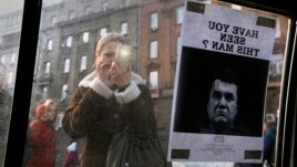 Một phụ nữ chụp ảnh lệnh 'truy nã' Tổng thống Victor Yanukovich tại Kiev.
