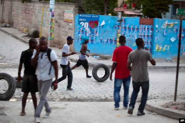 Supporters of Presidential candidate Moise Jean-Charles move tires before burning them during protests against official results just announced by the Electoral Council in the neighborhood of Delmas 33, Port-au-Prince, Haiti, Thursday Nov. 5, 2015.