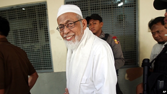 Militant cleric Abu Bakar Bashir walks from inside a holding cell to the start of his trial at a district court in Jakarta, Indonesia, June 6, 2011.
