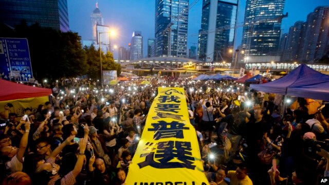 示威者在香港被占领金钟区亮出“我要真普选”黄色横幅 靠近 封神祭大叔：发表了博文《依法治国，请先解决香港的民主》。