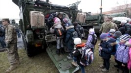 Fighting in Ukraine has affected life there. Here, children wait in line to see a U.S. militiary vehicle during the 