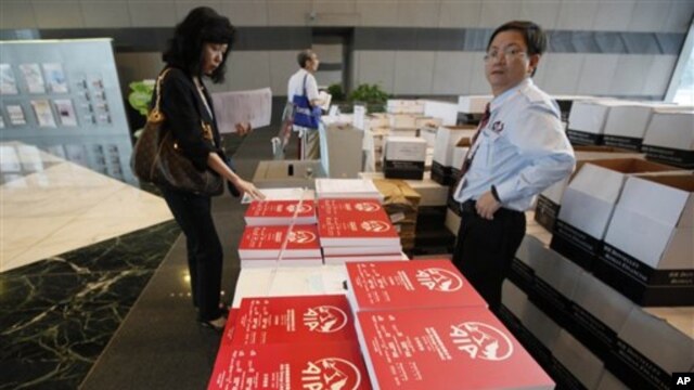 A prospective investor, left, takes a copy of the AIA (American International Group Inc) initial public offering (IPO) prospectus book at a bank in Hong Kong, 18 Oct 2010
