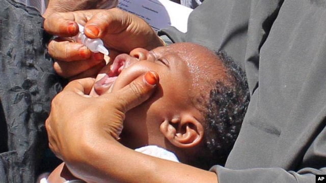 In this May 28, 2013 photo, vaccination workers give an anti-polio drop to a child in Mogadishu, Somalia.  