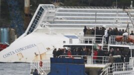 Relatives of victims stand on a ferry in front of the capsized cruise liner Costa Concordia outside Giglio harbor, Italy, January 13, 2013. 