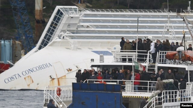 Relatives of victims stand on a ferry in front of the capsized cruise liner Costa Concordia outside Giglio harbor, Italy, January 13, 2013. 