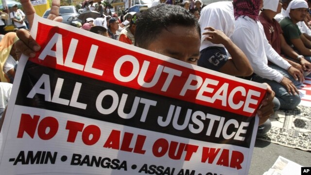 A Filipino Muslim flashes the peace sign as he holds a placard during a 'Prayer-for-Peace' rally near the Presidential Palace in Manila, Philippines, October 28, 2011. 