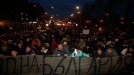 Protestors kneel as Bulgarian national anthem is played, as they block a main boulevard during demonstration against high electricity prices in Sofia, February 20, 2013.