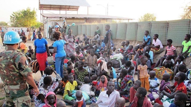 In this handout image provided by the United Nations Mission in South Sudan, Dec. 17, 2013, a United Nation soldier stands guard as civilians arrive at the UNMISS compound adjacent to Juba International Airport to take refuge.