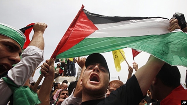 A Palestinian holds up a flag as he celebrates the reconciliation agreement between rival Palestinian factions Fatah and Hamas during a rally in Gaza City, May 4, 2011
