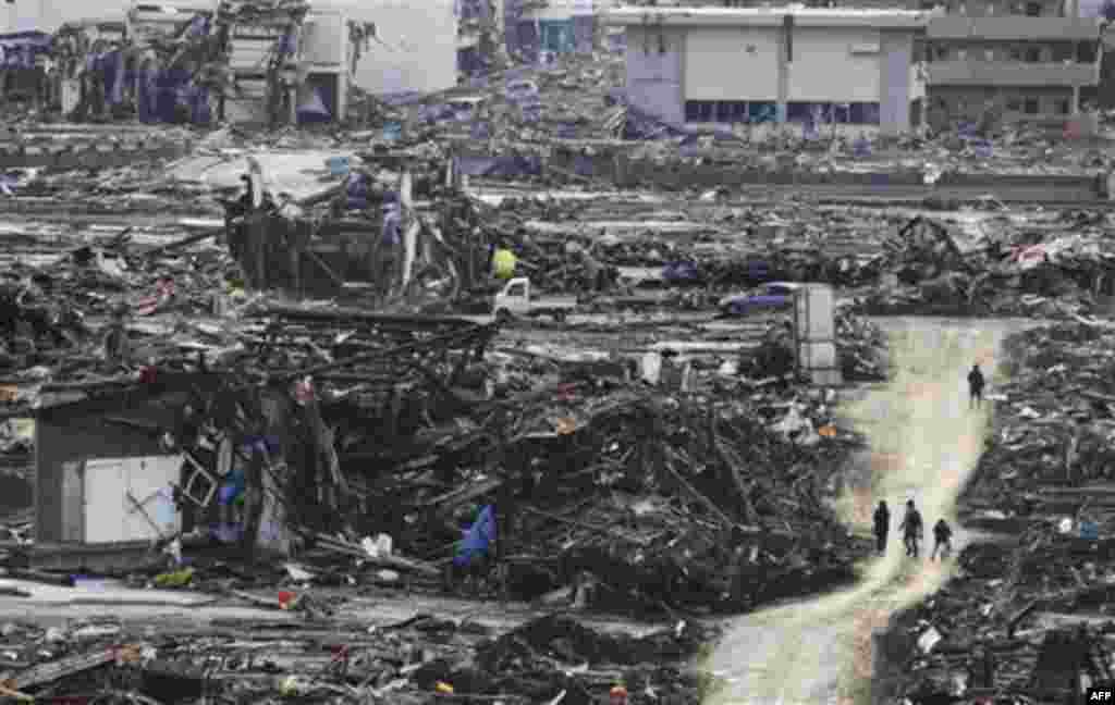 People walk on a makeshift dirt road among the rubble in Minamisanrikucho, northern Japan, Monday, March 14, 2011, three days after a powerful earthquake-triggered tsunami hit the country's east coast. (AP Photo/The Yomiuri Shimbun, Hiroaki Ono) JAPAN OUT