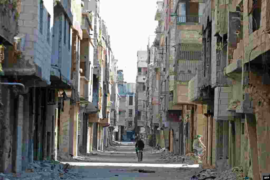 A man rides a bicycle past damaged buildings at the Yarmuk refugee camp in the southern suburbs of the Syrian capital Damascus. The regime of Syria&#39;s President Bashar al-Assad has recaptured vast territory from rebels and jihadists in the conflict that began in 2011.