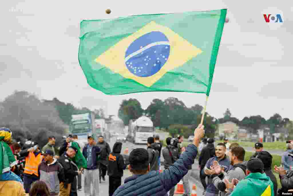 Un hombre agita una bandera brasileña mientras partidarios del presidente de Brasil Jair Bolsonaro, principalmente camioneros, bloquean una carretera durante una protesta por la derrota de Bolsonaro en la segunda vuelta de las elecciones presidenciales, en Curitiba, en el estado de Paraná, Brasil, el 1 de noviembre de 2022.&nbsp;