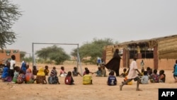 A teacher and her pupils play in a yard at a school created near a site for displaced people on the outskirts of Ouallam, Niger, on Oct. 26, 2022.