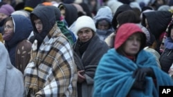 FILE - Refugees, mostly women and children, wait with other people to be transferred after arriving at the Medyka border crossing in Poland, fleeing the war in Ukraine, March 7, 2022.