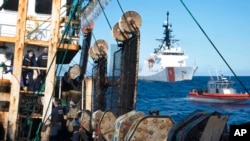 FILE - In this photo made available by the U.S. Coast Guard, guardsmen from the cutter James, seen at background right, conduct a boarding of a fishing vessel in the eastern Pacific Ocean, on Aug. 4, 2022. 