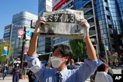 A man distributes an extra edition of Yomiuri newspaper reporting about North Korea's recent missile launches near Japan, in Tokyo, Nov. 3, 2022.