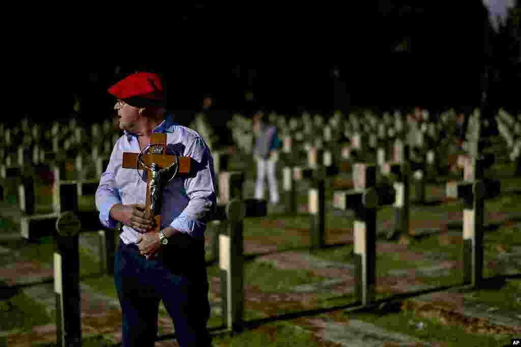 A person wearing the traditional red beret of the Requetes, a rebel militia that fought against the republican government, holds a crucifix in memory of the rebels killed in the Spanish civil war (1936-1939) during All Saints Day, a Catholic holiday to reflect on the saints and deceased relatives, at the state cemetery in Pamplona, northern Spain.