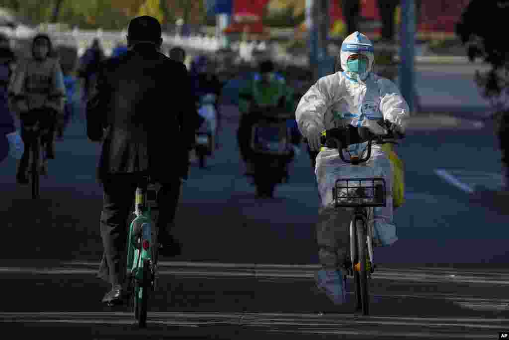 A worker in protective gear rides on a street as she heads to take COVID-19 samples from residents who have been under home quarantine in Beijing. The ruling Communist Party is enforcing a &quot;Zero COVID&quot; policy that has closed areas throughout China for weeks to try to isolate every case.&nbsp;