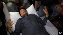 In this photo released by former Pakistani Prime Minister Imran Khan's party, Pakistan Tehreek-e-Insaf, Khan, who was injured in a shooting incident, is seen on a stretcher after the incident, in Wazirabad, Pakistan, Nov. 3, 2022.