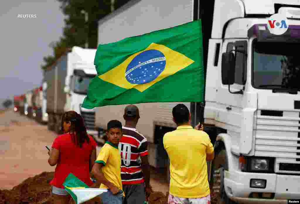 Un hombre sostiene una bandera brasileña junto al bloqueo de la carretera BR-251, que fue parcialmente despejada, después de que los partidarios del presidente de Brasil, Jair Bolsonaro, bloquearan la carretera durante una protesta contra el presidente electo Luiz Inácio Lula da Silva, que ganó un tercer mandato tras la segunda vuelta de las elecciones presidenciales, en Planaltina, Brasil, el 1 de noviembre de 2022.&nbsp;