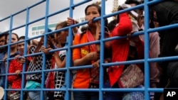 Cambodian migrant workers stand in a truck as they arrive from Thailand at a Cambodia-Thai's international border gate in Poipet, Cambodia, Tuesday, June 17, 2014. 