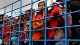 Cambodian migrant workers stand in a truck as they arrive from Thailand at a Cambodia-Thai's international border gate in Poipet, Cambodia, Tuesday, June 17, 2014. 