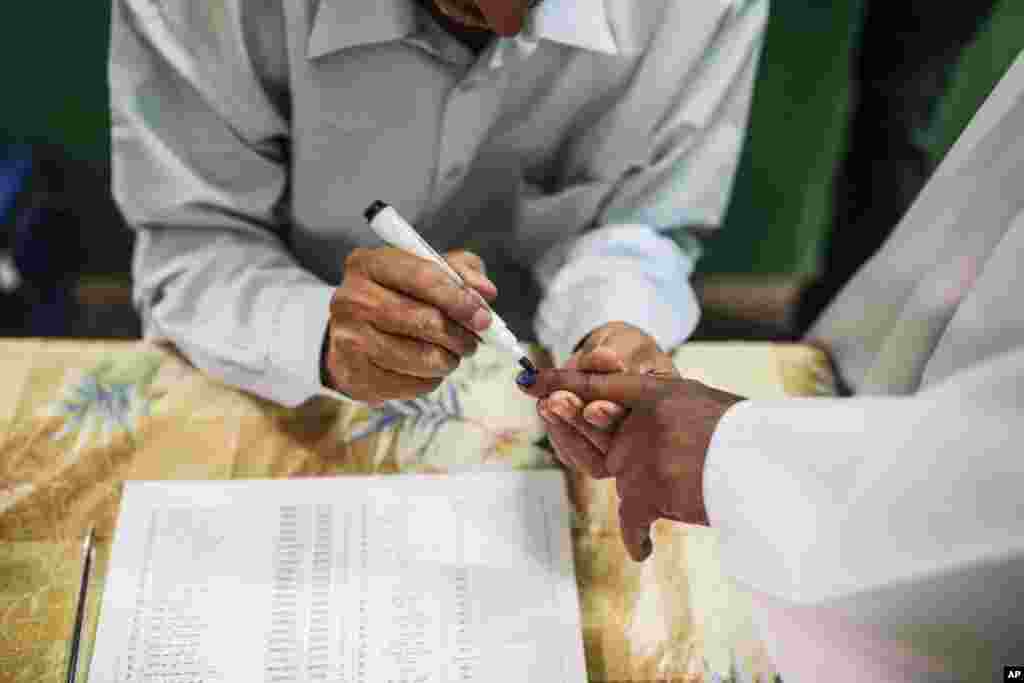 A man gets his nail painted with blue ink as proof of voting just before casting his ballot on the first day of Sudan's presidential and legislative elections, in Khartoum, April 13, 2015.