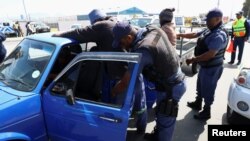 Police officials search motorists in what the Cape Town mayor's office describes as the "biggest anti-crime operation" in the city's history, Cape Town, South Africa, Oct. 12, 2022.