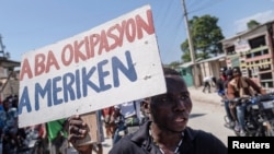 Un hombre sostiene un cartel que reza "abajo la ocupación estadounidense" durante una protesta para exigir la renuncia del primer ministro haitiano, Ariel Henry, en la capital Puerto Príncipe, el 17 de octubre de 2022.