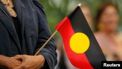 FILE - A woman holds an Aboriginal flag, Feb. 13, 2008. 