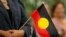 FILE - A woman holds an Aboriginal flag, Feb. 13, 2008. 