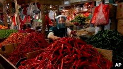 FILE - Seorang pedagang cabe merah di pasar tradisional di Jakarta, mengenakan masker di tengah pandemi COVID-19, 2 Juni 2020. (AP/Tatan Syuflana). Komoditas utama seperti cabe merah dituding sebagai salah satu penyebab menyebabkan deflasi.