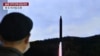 Seorang pria menonton layar televisi yang menyiarkan siaran berita uji coba rudal Korea Utara, di sebuah stasiun kereta api di Seoul pada 2 November 2022. (Foto: AFP)