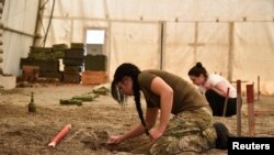 Una mujer participa en un entrenamiento sobre la remoción de minas terrestres y otras municiones sin detonar, preparado para un grupo de ucranianos, incluidos civiles y oficiales del ejército, en medio de la invasión rusa de Ucrania en Peja, Kosovo, el 31 de mayo de 2022.